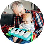 a man holding a baby and playing with a piano.