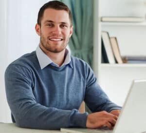 man smiling at his laptop