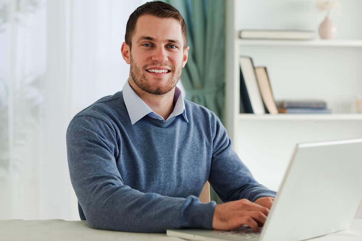 man smiling at his laptop
