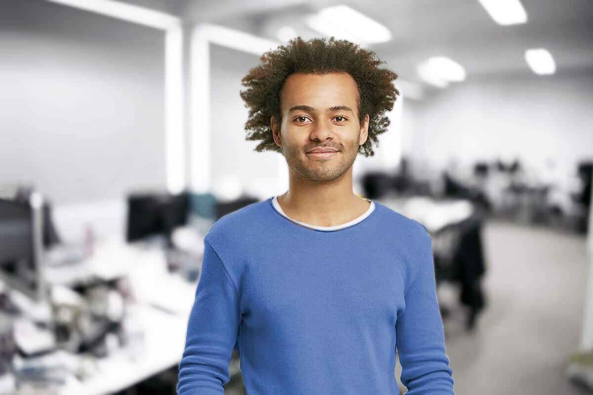 a man with curly hair standing in an office.