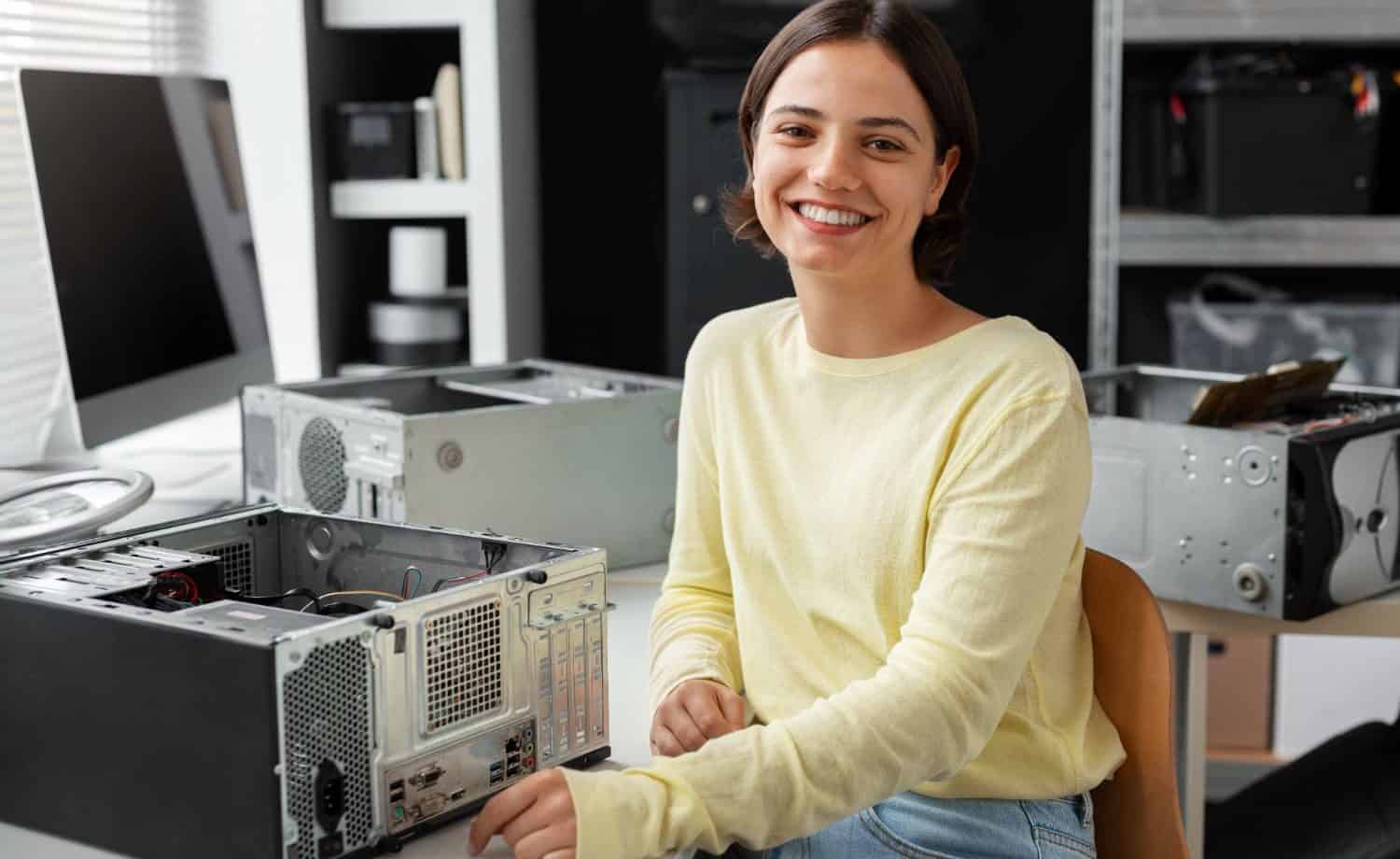 Woman working on open desktop computer and smiling at the camera