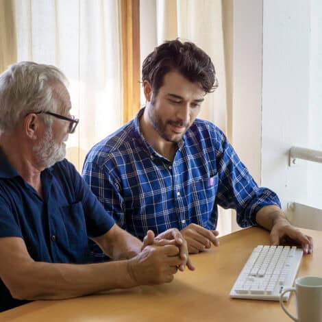 Technician computer tutoring senior man in home