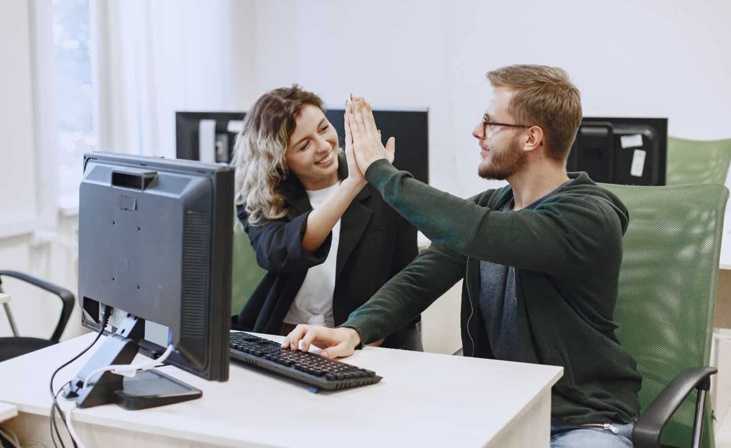 Man and woman high-fiving each other after fixing a computer themselves