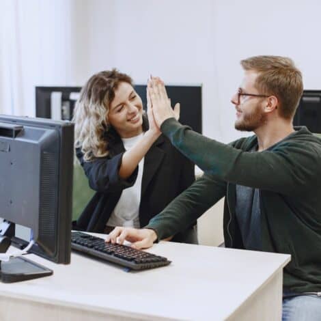 Man and woman high-fiving each other after fixing a computer themselves