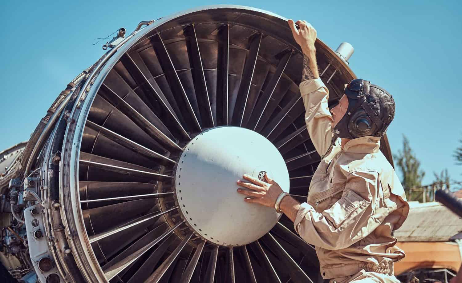 Vintage pilot in front of a huge airplane fan, implying the computer fan is loud as an airplane