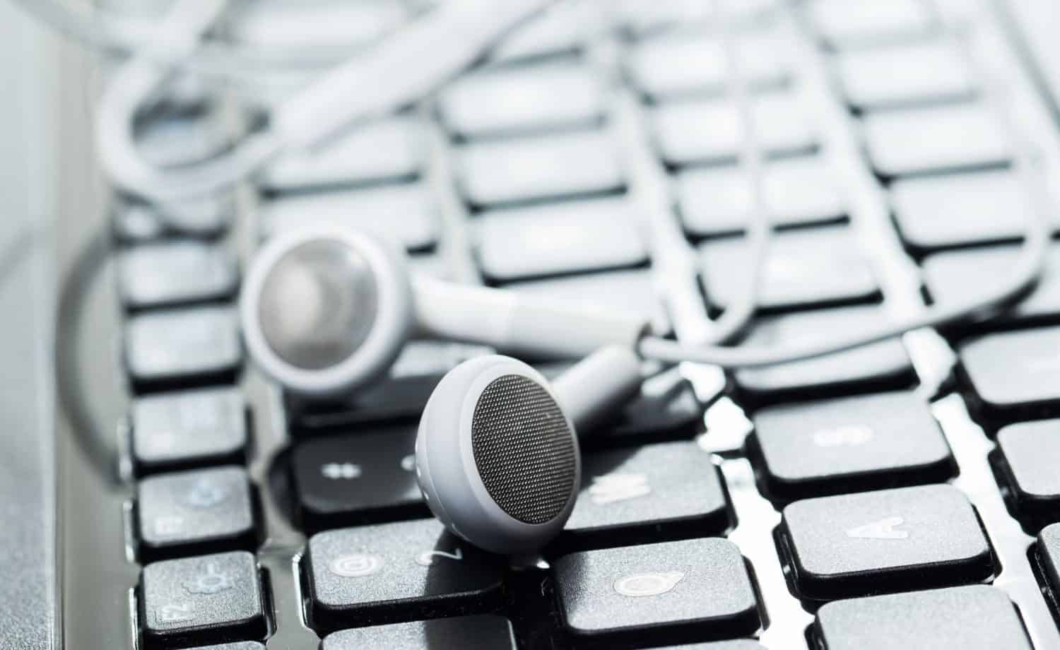 laptop keyboard with earbuds on top