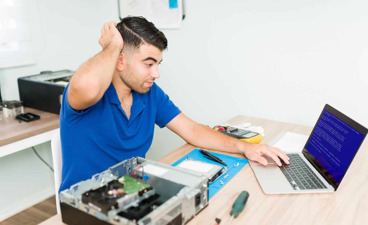 Man frustrated with blue screen error on laptop