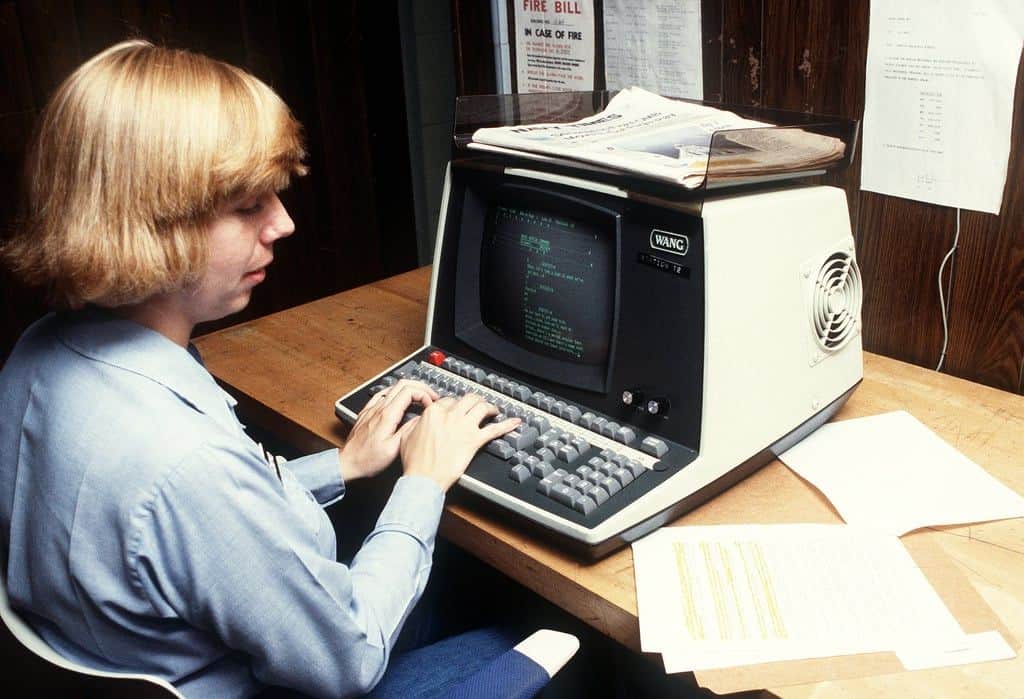 A woman typing on a vintage computer