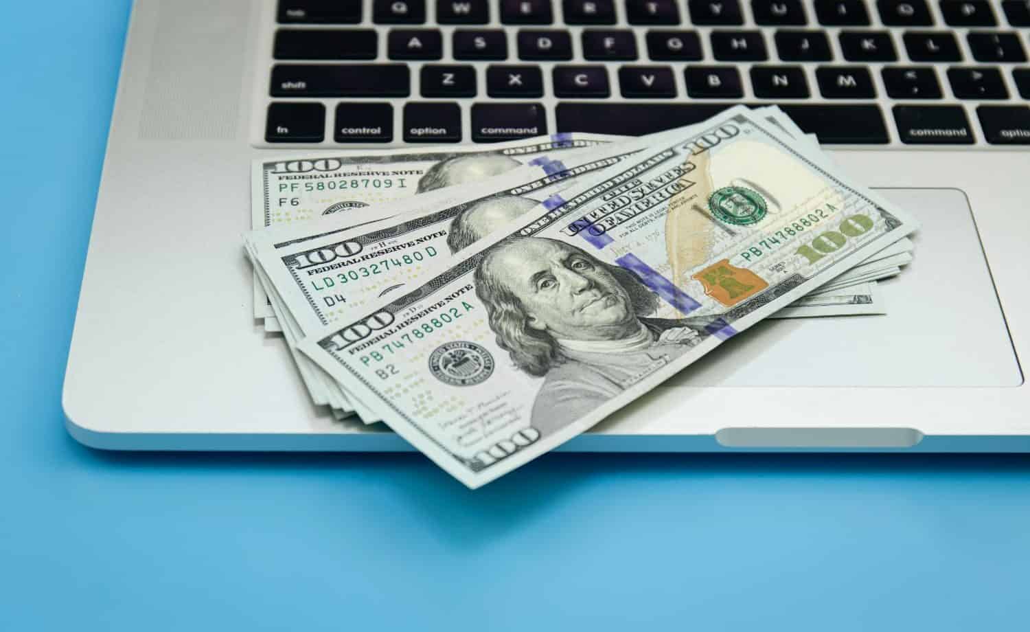 a laptop with $100 bills on it