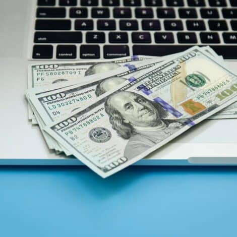 a laptop with $100 bills on it