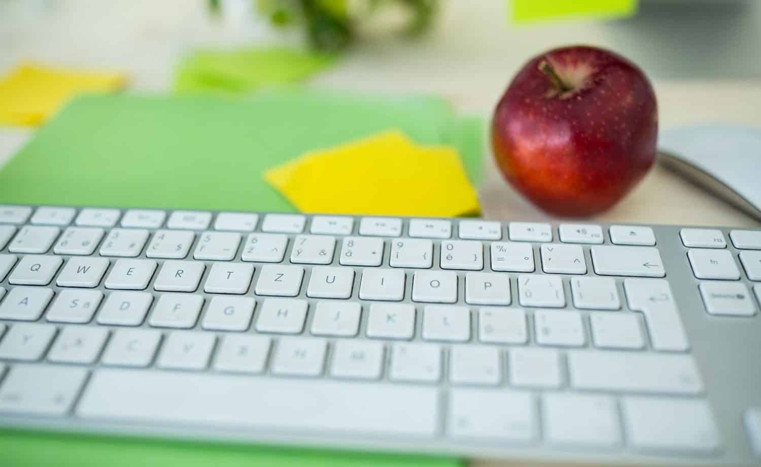 a computer keyboard and an apple