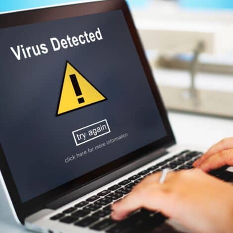 laptop screen with "virus detected" alert.