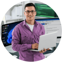Computer Repair Services by Geeks On Command - A Computer Support Company Smiling, confident young male IT professional in glasses and a purple button-down providing computer support on a laptop in a home office, with dual monitors showing a tech support email about Geeks On Command's in-home computer repair, remote IT support, and data recovery services.