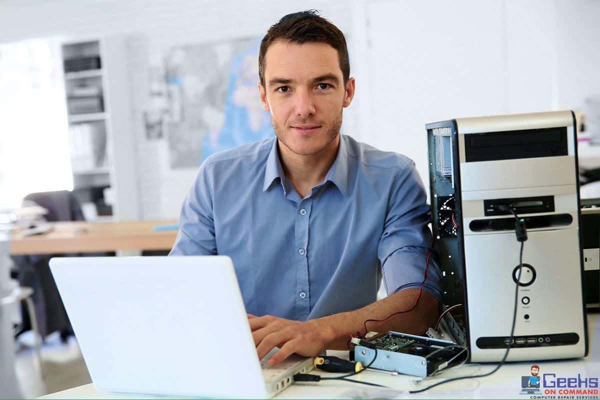 Technician performing data recovery services by Geeks On Command, working on a desktop computer and laptop to retrieve data from a damaged hard drive.