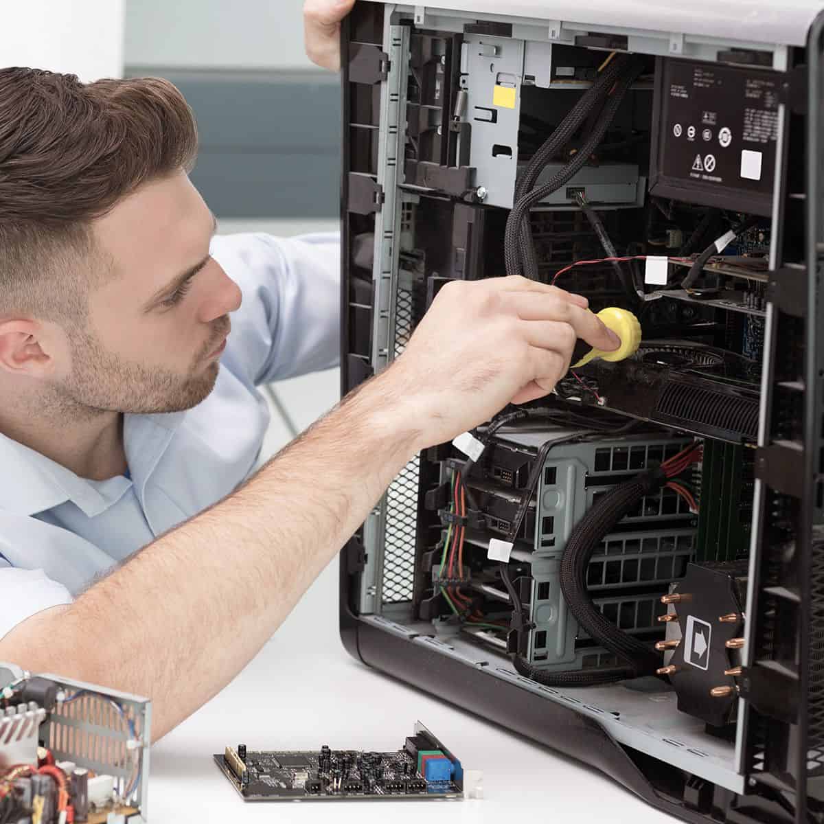 IT technician installing computer components in opened desktop tower