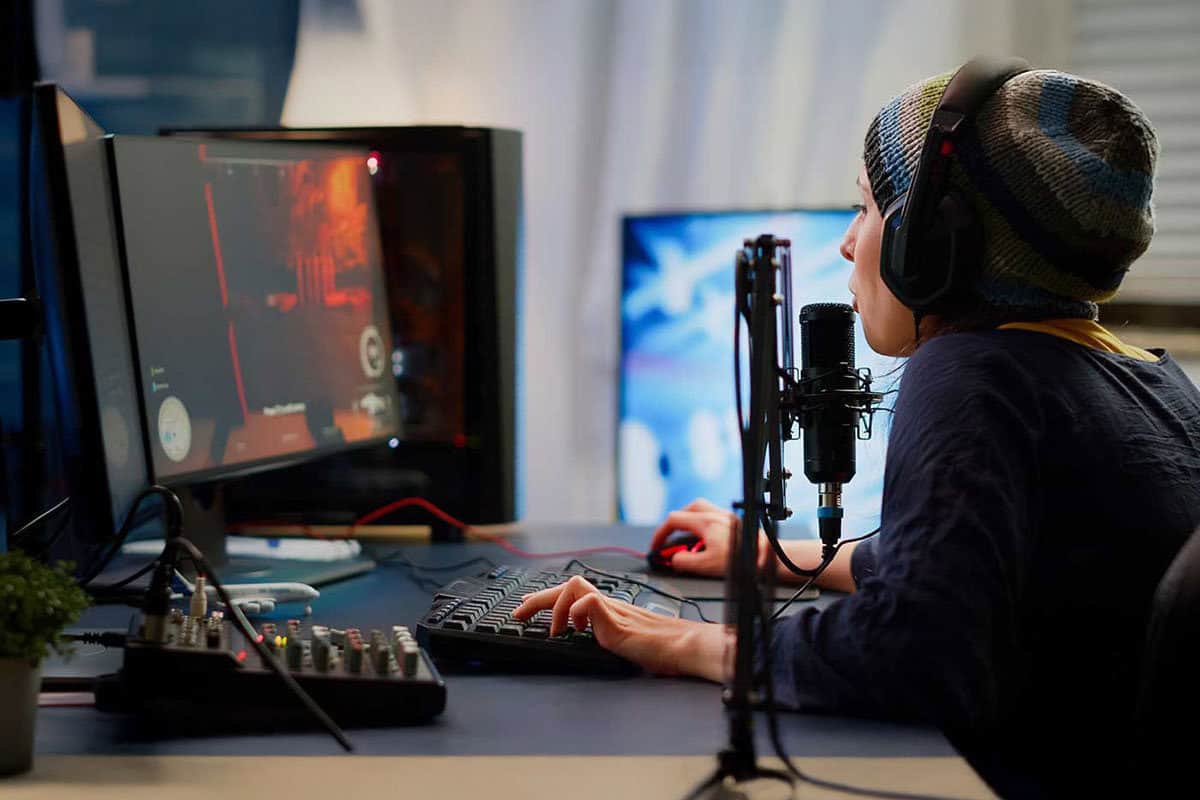 Person with headphones and microphone at streaming PC setup with dual monitors, representing streaming computer configuration services.